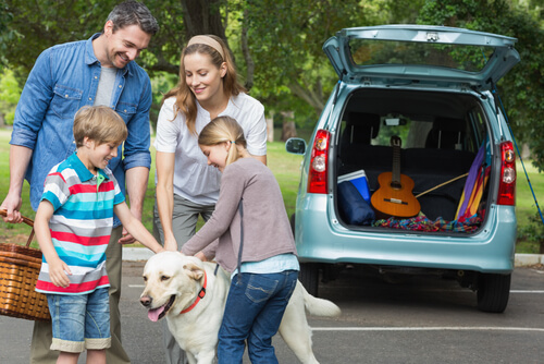 Un famille et leur chien face au coffre ouvert d'une voiture