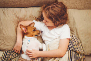 Une petite fille allongée sur son lit avec son chien.