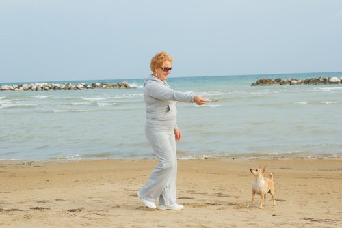 Kvinne trener på stranden med hund.