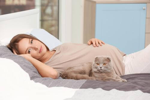 Zwangere vrouw ligt op bed met kat