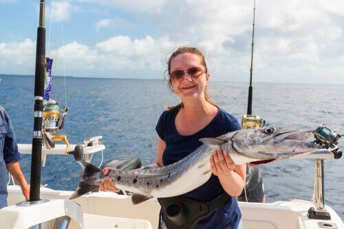 Kvinna som har fångat den aggressiva barracudafisken