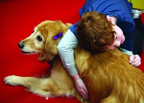 Ett barn i terapi ger en hund en stor kram.