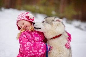 Dog licking a little girl on the face