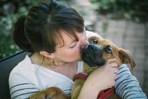 A woman kissing a dog