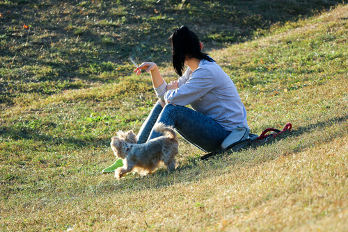 A woman smoking around her dog