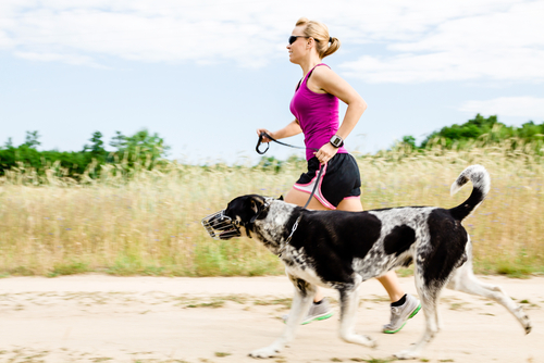 Woman running with her dog that has a muzzle on