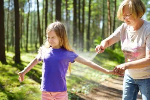 A girl getting bug spray to prevent diseases transmitted by ticks.