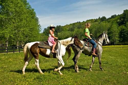 Girls riding horses in a field.