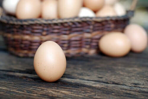 Some chicken eggs in a basket on a table.