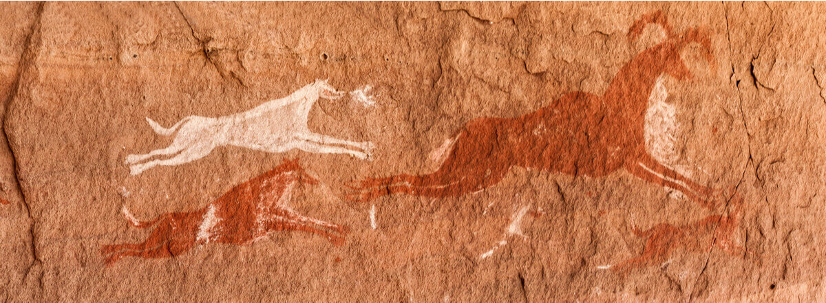 Prehistoric dogs chasing prey in a cave painting.