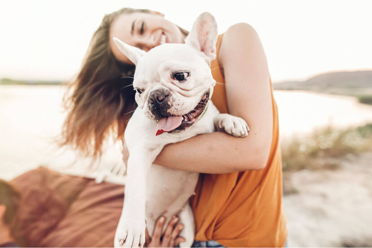 An owner holding her dog on the beach.