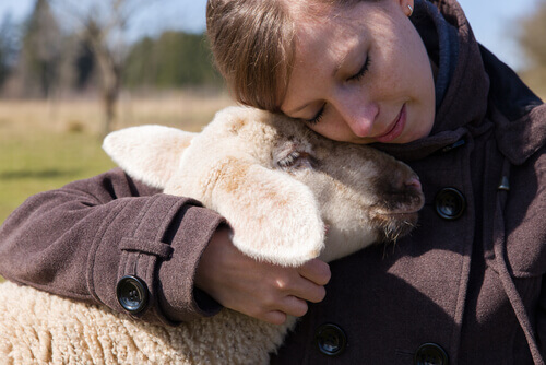 A lady hugging a baby goat.