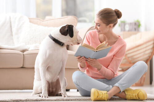 A woman reading a book to her dog.