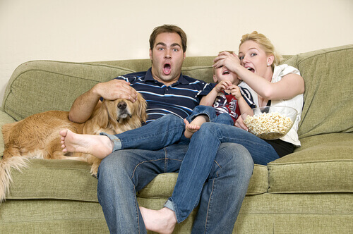 A family watch a movie on their sofa.